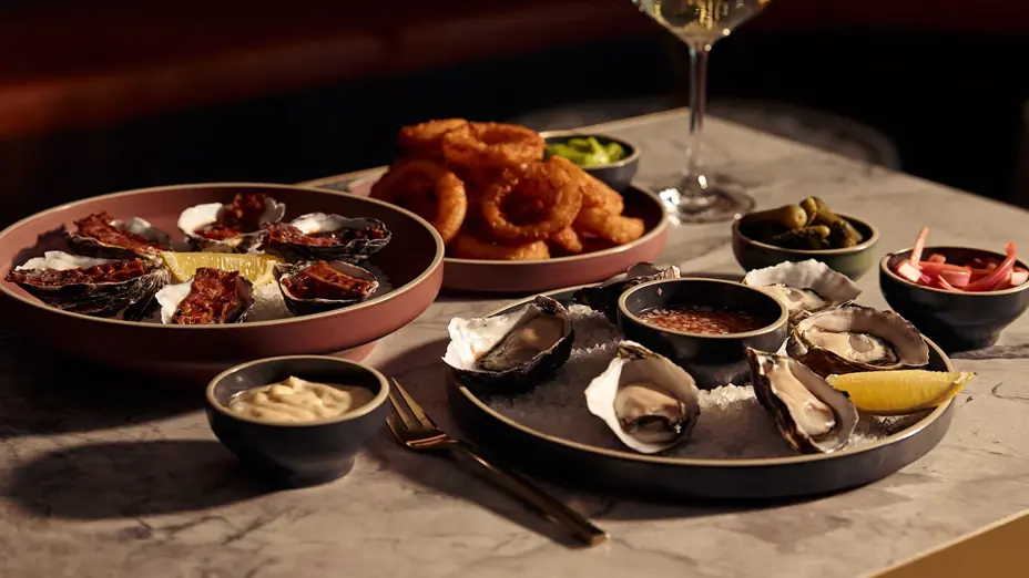 Arrangement of oyster and calamari dishes and white wine