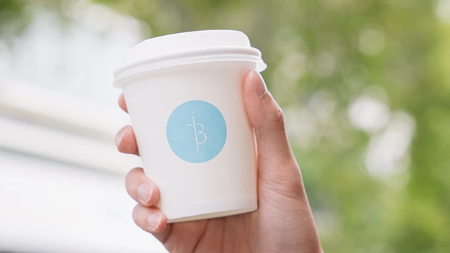 Hand holding Industry Beans coffee cup
