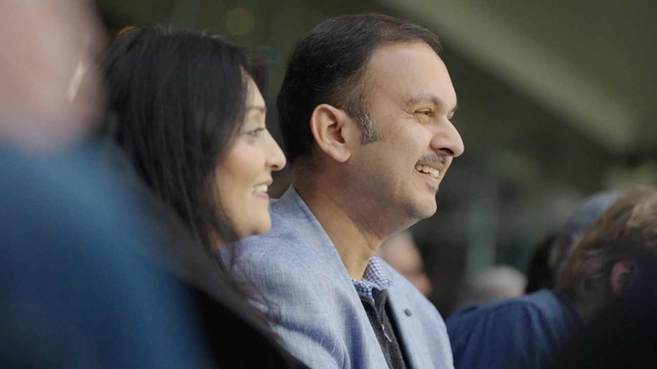 Two people seated in a stadium, smiling