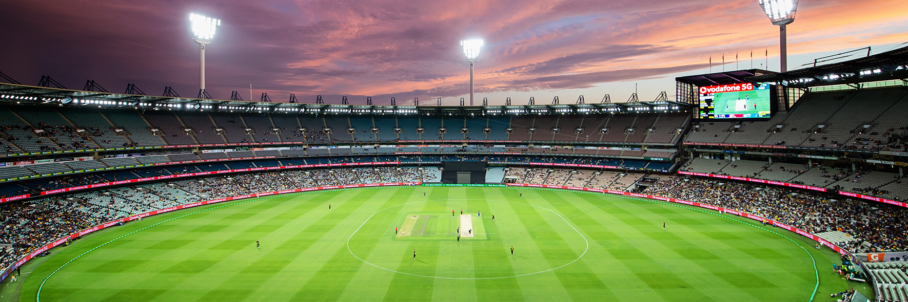 A wide view of the MCG arena during a T20 International with a sunset in the background