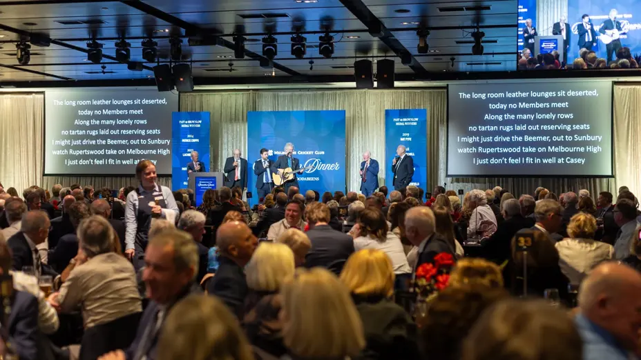 Guests seated at tables as the Coodabeens perform song lyrics about past Brownlow Medal winners