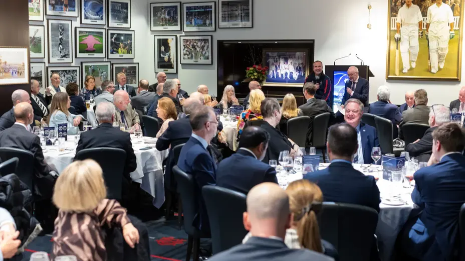 Guests seated at function tables smiling and listening to speakers