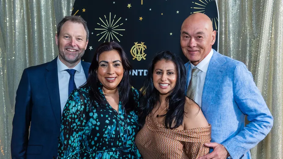 Four guests posing in front of the MCC New Year's Eve backdrop