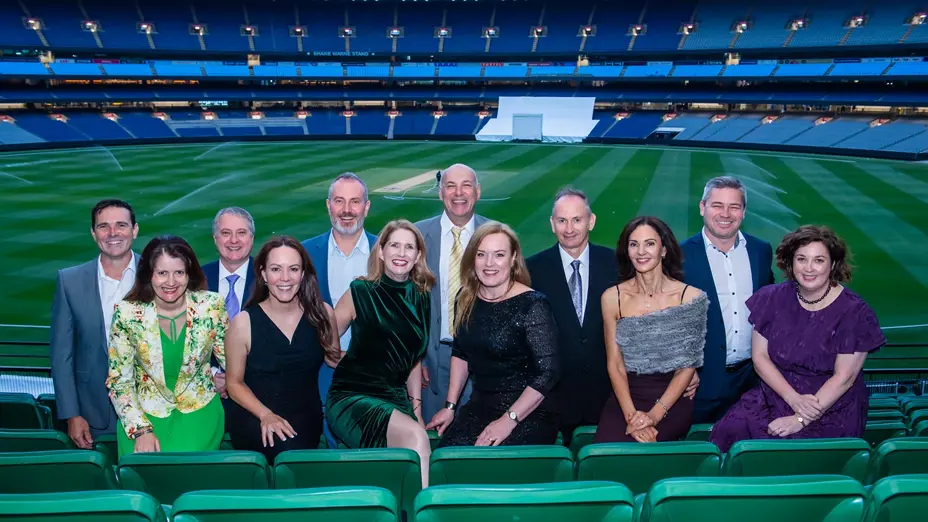 Guests posing together in the stands overlooking the MCG arena at dusk
